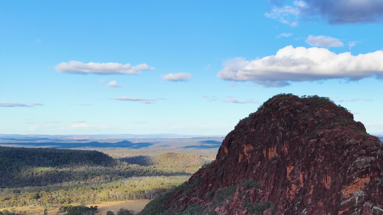 Drone pans across Timor Rock, revealing vast Australian landscape under bright daylight and clear skies