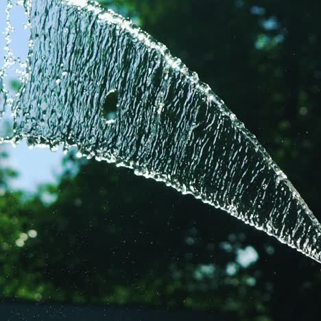 stream of water spraying from garden hose, close up. watering the green grass. slow motion.