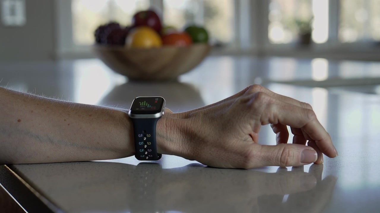 Rotating forearm and hand activating smartwatch on kitchen counter, checking activity progress
