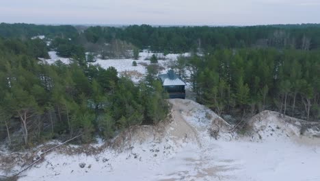 aerial establishing view of baltic sea coast on a overcast winter day, a tiny gray holiday house at the beach with white sand, coastal erosion, climate changes, wide ascending orbiting drone shot