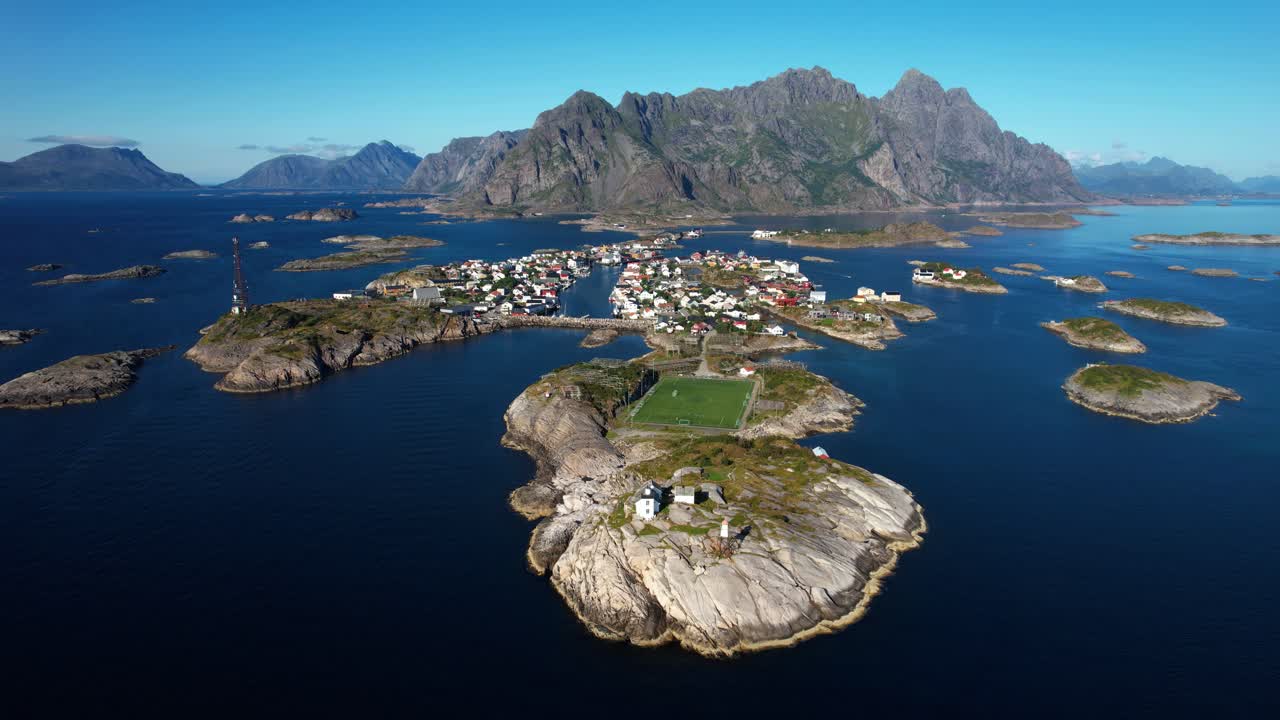 Aerial view of Henningsvær coastal town in Lofoten, with islands, sea, and iconic football field. 4K