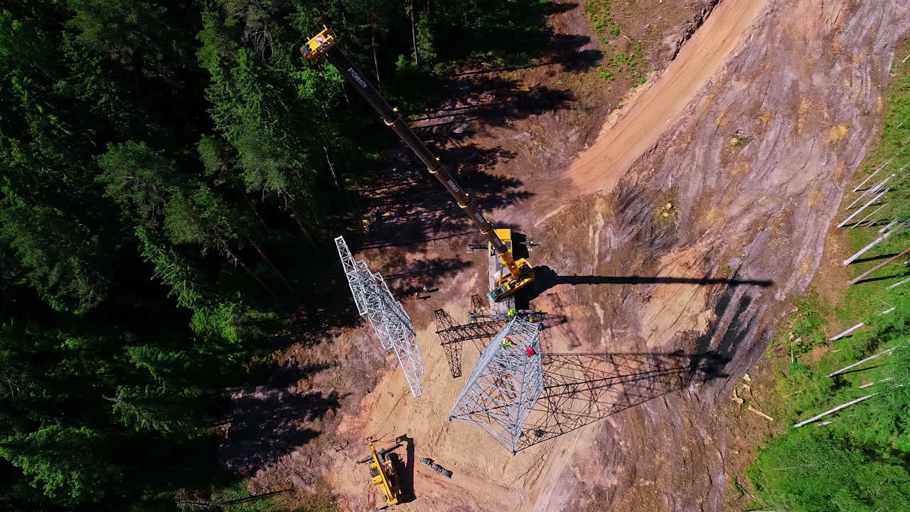 toma aérea de arriba hacia abajo del trabajador instalando y levantando una grúa pilón de transmisión de metal