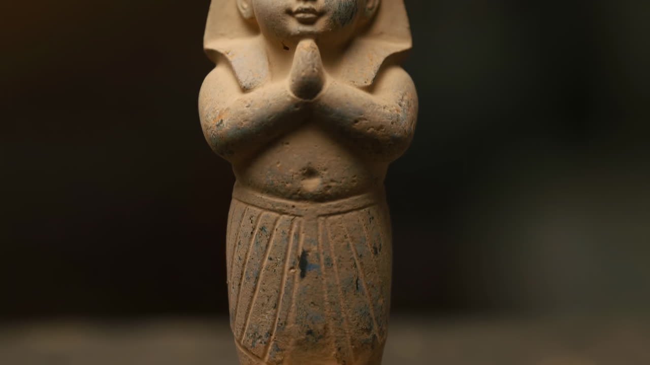 Primo piano di antica statuetta funeraria egizia, shabti in terracotta con braccia incrociate, patina invecchiata e dettagli sottili