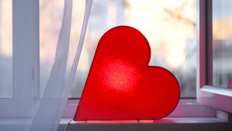 lámpara en forma de corazón roja en un alféizar de la ventana