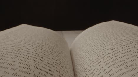 a camera shot floating across an open book with a black background and the book is later closed