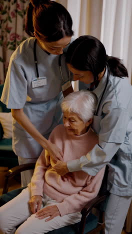 caregivers assisting an elderly woman