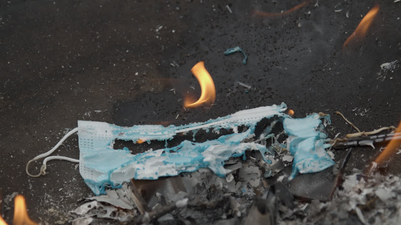 máscara facial covid-19 usada quemándose lentamente al final de la pandemia