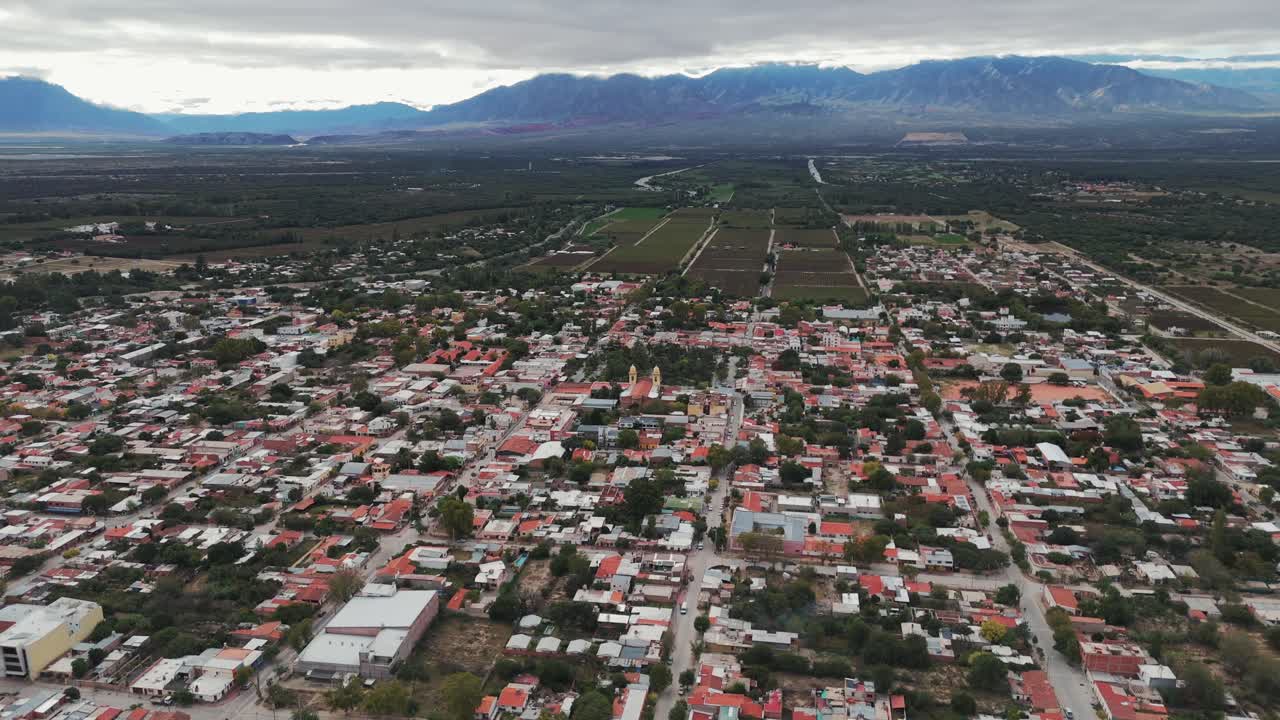 tomada aérea de un dron de la ciudad de cafayate de salta en argentina con la cordillera andina y las granjas de viñedos en el fondo