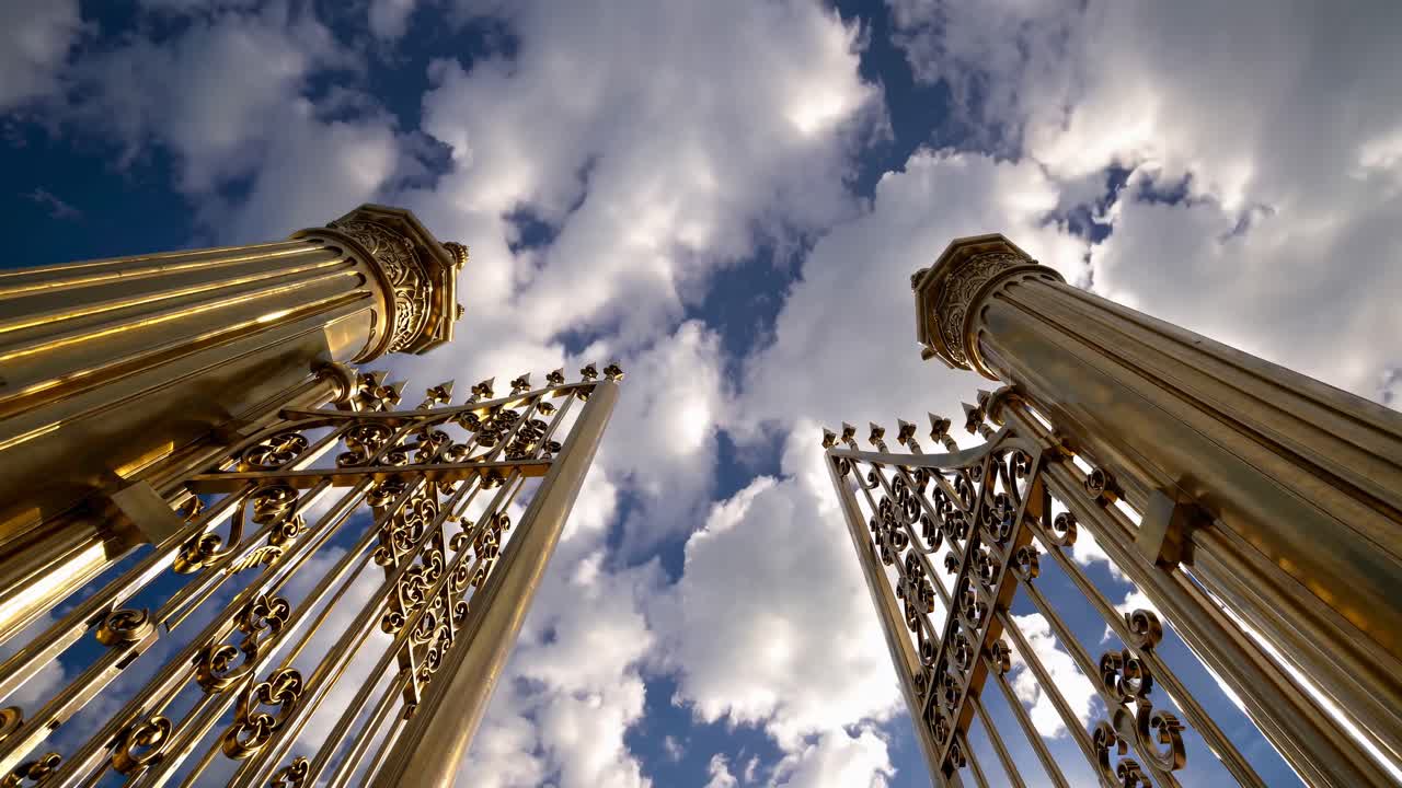 Low-angle shot of ornate golden gates against a cloudy sky, creating a majestic and grand entrance