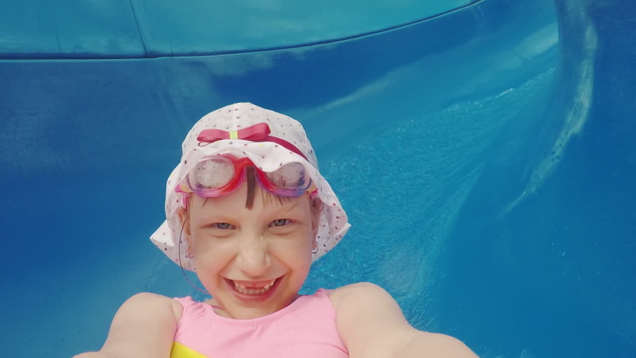 chica divertida en panamke blanco paseos desde el tobogán de agua y hace un ridículo selfie en la cámara