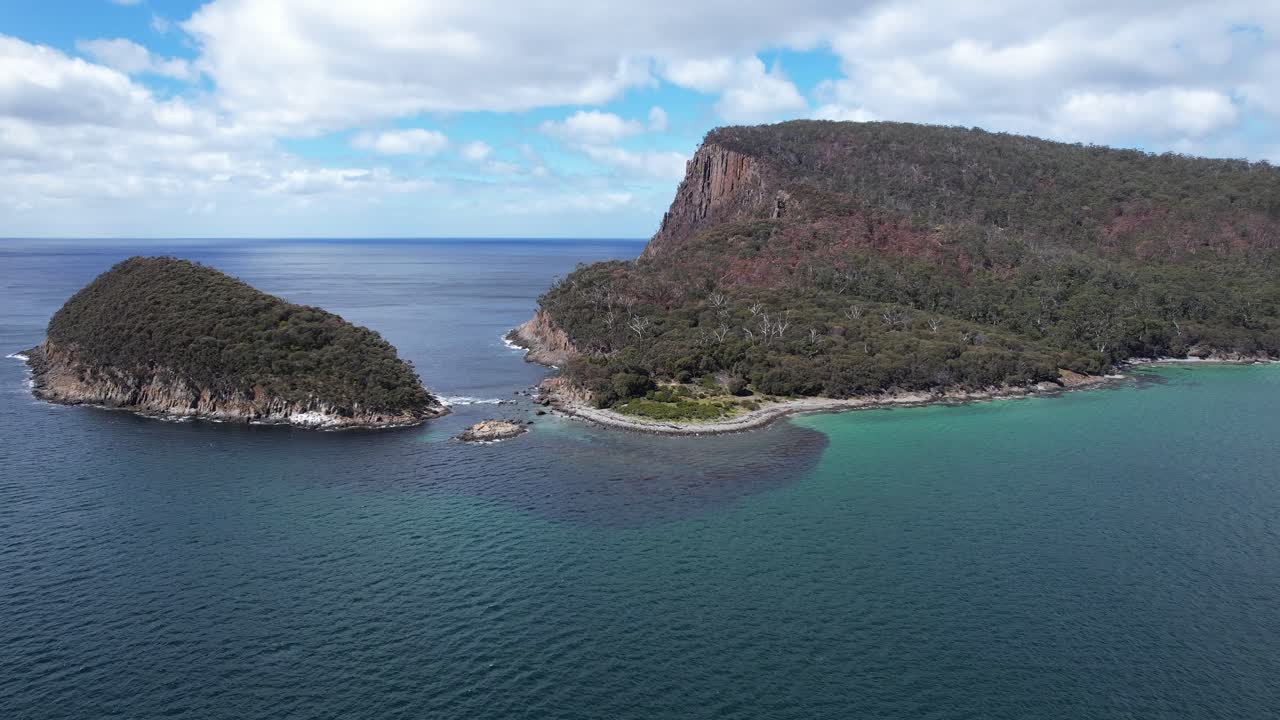 Passeggiata a Fluted Cape e isola dei Pinguini circondata dall'oceano blu in Tasmania, Australia - Ripresa aerea