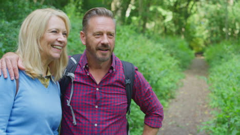 mature couple in countryside hiking along path through forest together