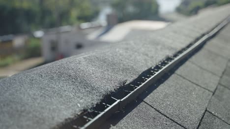 close-up of a professional inspecting the ridge cap on a roof for quality and proper installation.