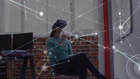 Animation-Eines-Netzwerks-Von-Verbindungen-über-Eine-Geschäftsfrau,-Die-Im-Büro-Ein-VR-Headset-Verwendet