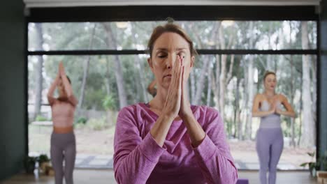 focused diverse women meditating together on mats in yoga class with female coach, slow motion