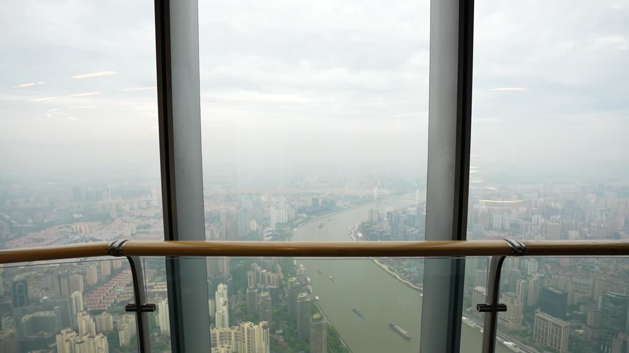 Slow motion capture of a visitor strolling the observation level and taking in wide views over the Huangpu River and cityscape. Shanghai, China