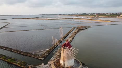 aerial circling shot of salt evaporation ponds and salt mounds on sicily island during beautiful sunset day