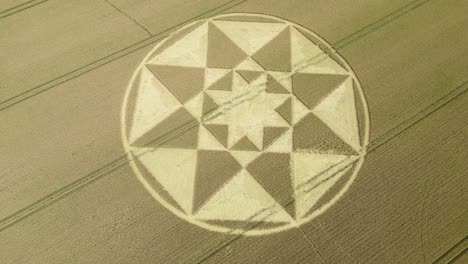 Star-shaped-crop-circle-pattern-on-golden-Micheldever-wheat-field-aerial-view,-Slowly-flying-above,-2023