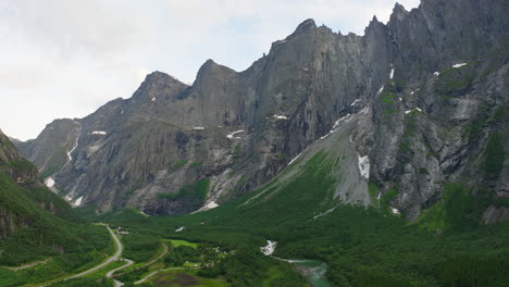 Vista-Aérea-Panorámica-Mientras-El-Río-Rauma-Fluye-Por-El-Valle-Junto-Al-Muro-De-Trolls,-Noruega