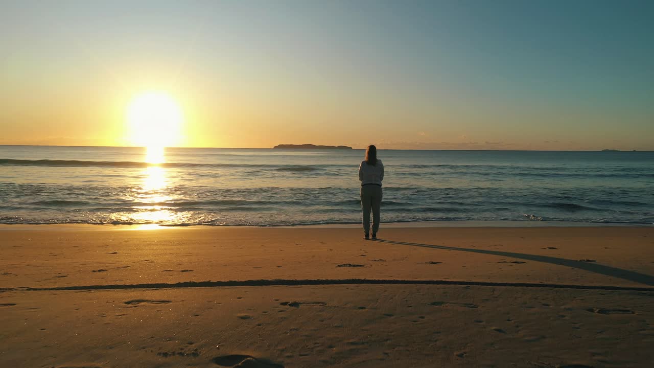 여자는 바다 근처의 해변에서 혼자 서 있습니다.