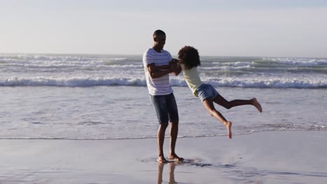 padre afroamericano y su hija jugando en la playa
