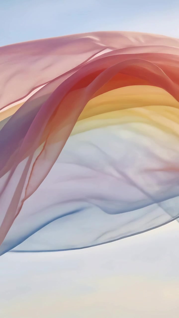 Vertical video: Wafting sheer multicolored fabric drifting across pale blue sky by soft breeze