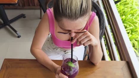 mujer disfrutando de un cóctel púrpura en un café
