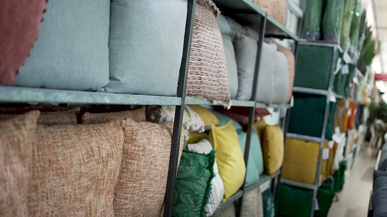 Bright and soft cushions in various colors and textures fill the shelves of a home décor shop. Shoppers explore the stylish options to enhance their living space