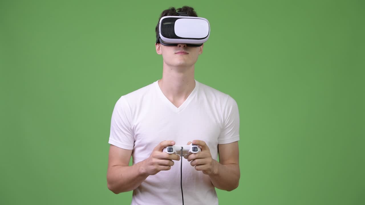 Giovane uomo affascinante che gioca ai videogiochi mentre usa un visore per la realtà virtuale