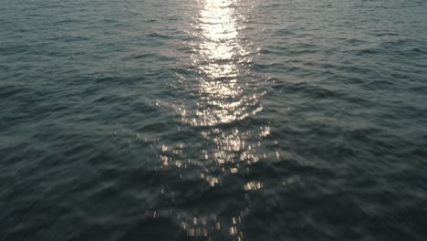 cinematic drone aerial flying over the water revealing the sunset