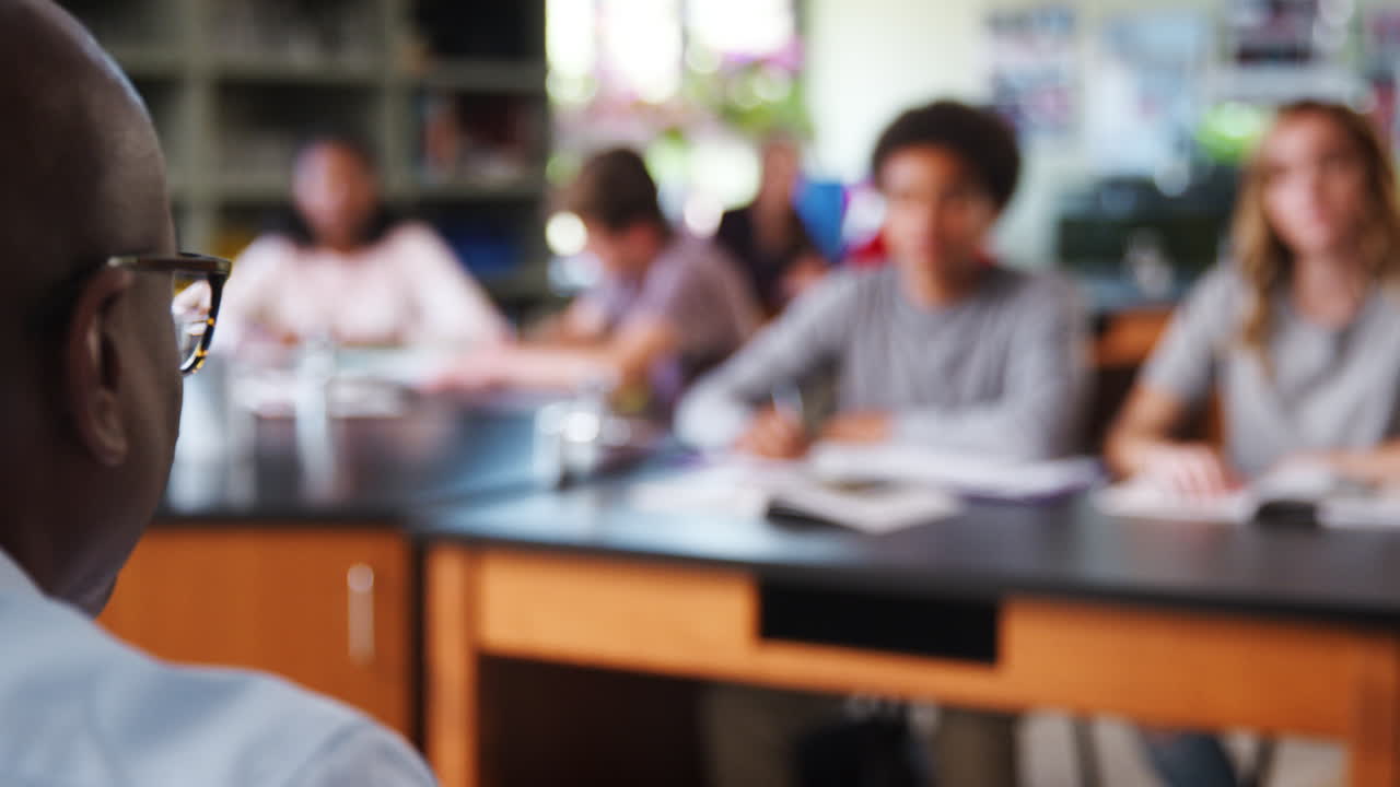 Pull Focus Shot Of Male High School Tutor Teaching Students In Biology Class