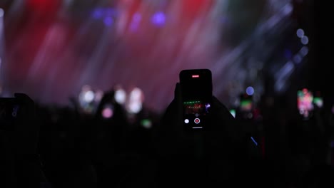 Fans-recording-video-with-smartphones-at-live-concert,-music-group-performing-on-stage