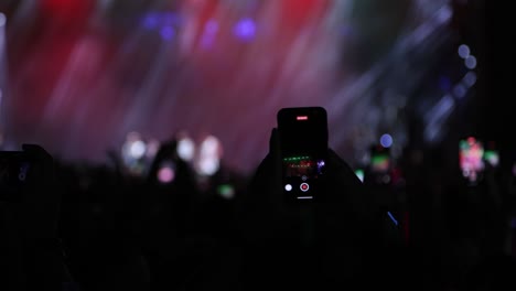 fans recording video with smartphones at live concert, music group performing on stage