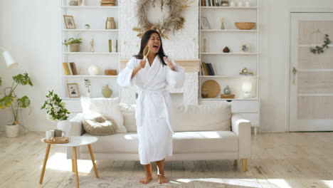 woman dancing and singing in bathrobe with hairbrush as a microphone