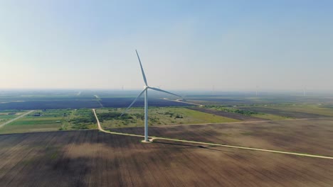 Weitwinkel-Windkraftanlage,-Windturbine-Auf-Ackerland,-Drohnenaufnahme-Aus-Der-Luft,-Windpark-An-Sonnigem-Tag,-Blauer-Himmel,-Dunstiger-Morgen,-Übersichtsflug,-Grüne-Energie,-Texas,-Windpark-San-Roman