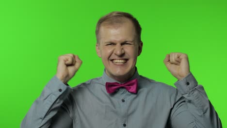 happy man raising fist in victorious gesture, dancing, celebrating great success, enjoying lucky day