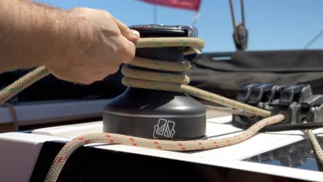 Close-up-shot-of-a-sailor-wrapping-rope-around-the-winch-during-summer-at-Le-Grau-du-Roi