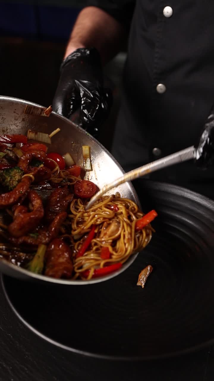 chef cocinando fideos fritos con verduras y carne