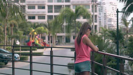 mujer joven delgada con cabello largo se para contra las palmas de las manos