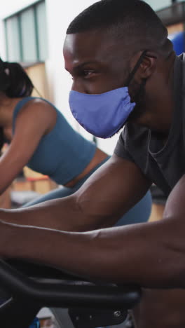 diverse woman and man wearing face masks exercising at gym