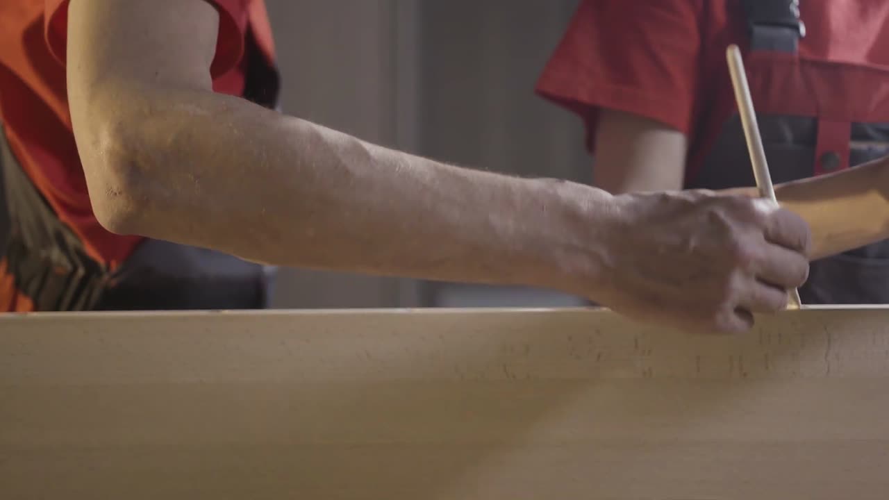 dos personas trabajando juntas en un panel de madera usando pegamento