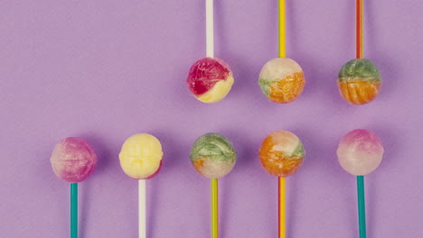 sweet lollipops appear on color purple background. bright texture sugar candies close up top view. composition of favorite children's summer sweets. studio shot for shop, supermarket, confectionery