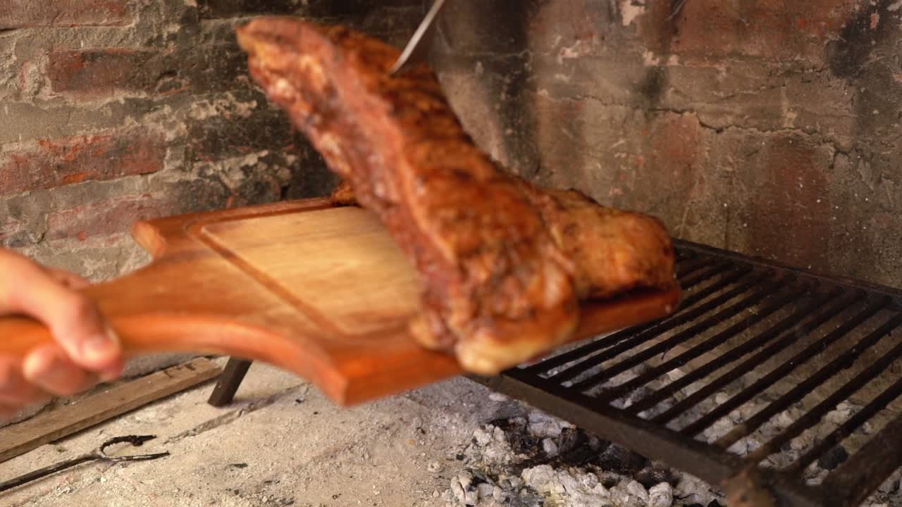 persona sacando carne de la parrilla en un asado argentino