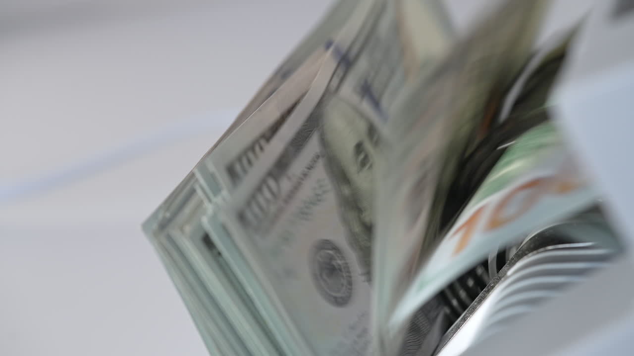 Mechanism in cash counting machine turning quickly. US hundred dollar banknotes counted in the money counting equipment. Close up.