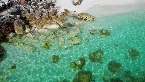 closeup, top down view of paradise beach rocky shoreline, covered by white marble pebbles, clear tropical sea water, marble beach, thassos island, greece