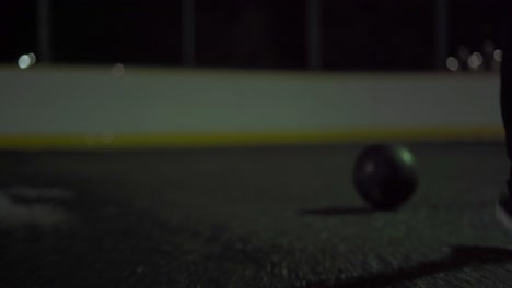 Female-running-with-black-pants-to-get-a-basketball-on-an-outdoor-court-in-the-dark-with-wet-pavement