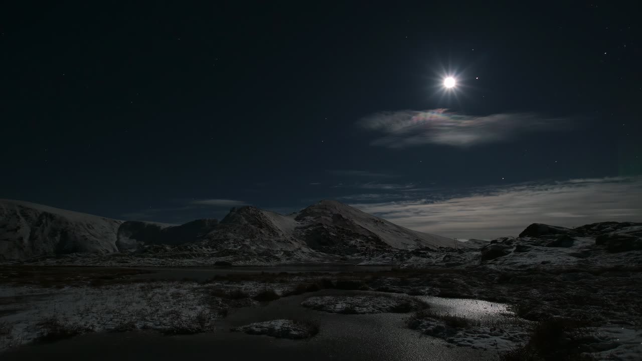 Aurora over mountains with moon and bit of cloud cover