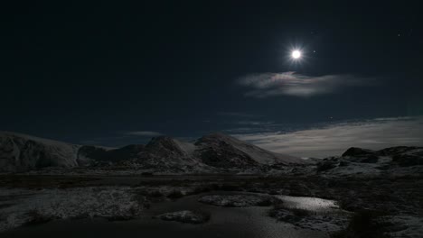 aurora sobre las montañas con luna y un poco de cubierta de nubes