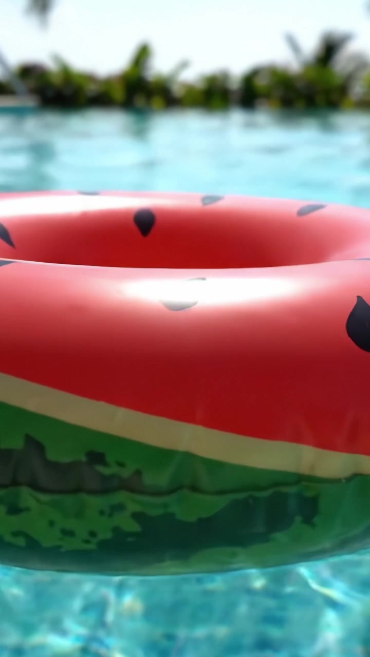 A Vibrant Watermelon Float Ring Gliding on Crystal Clear Swimming Pool Water Under Bright Sunshine