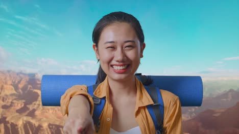 close up of asian female hiker with mountaineering backpack smiling, touching her chest, and pointing to camera while traveling at the top of mountain